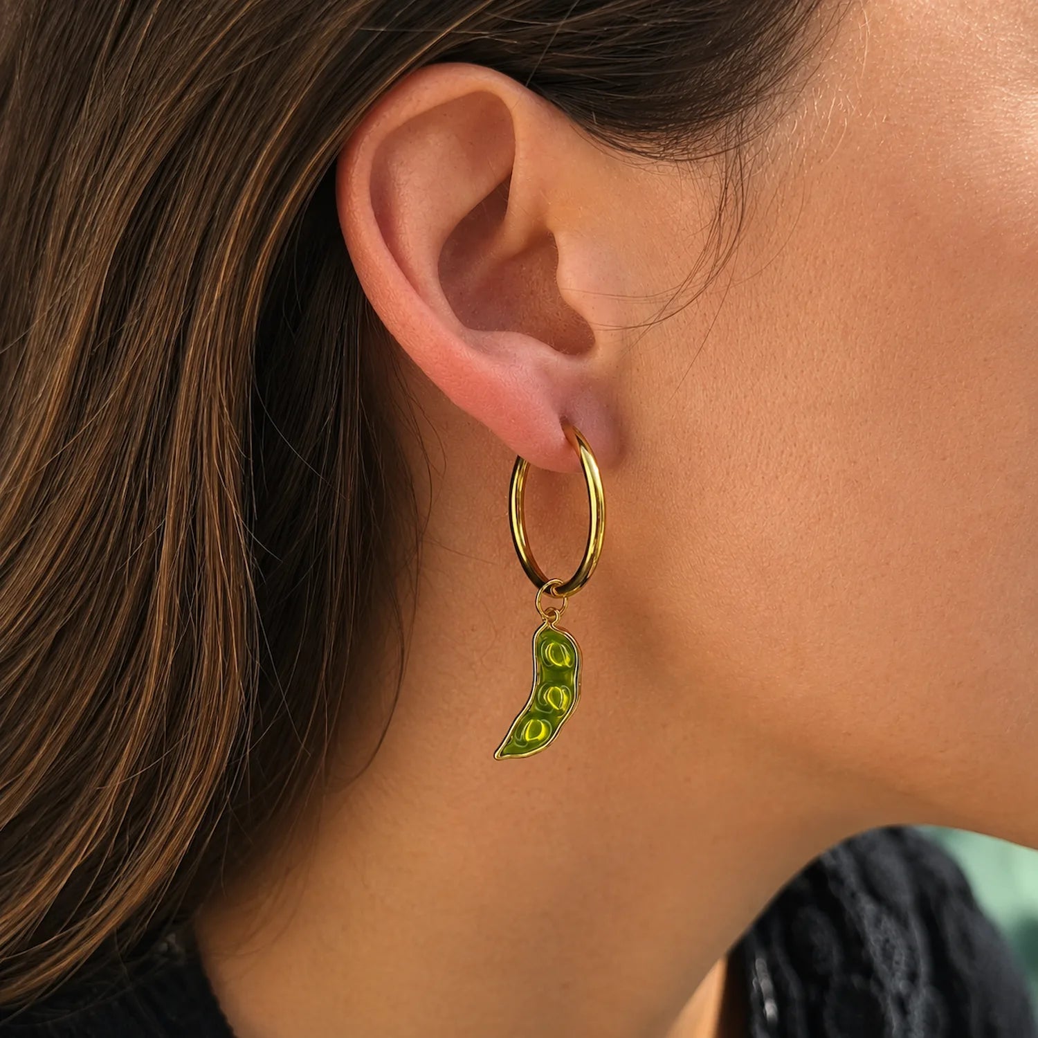 boucle d’oreille créole dorée avec charm haricot petit pois vert porté dans une ambiance douce et lumineuse