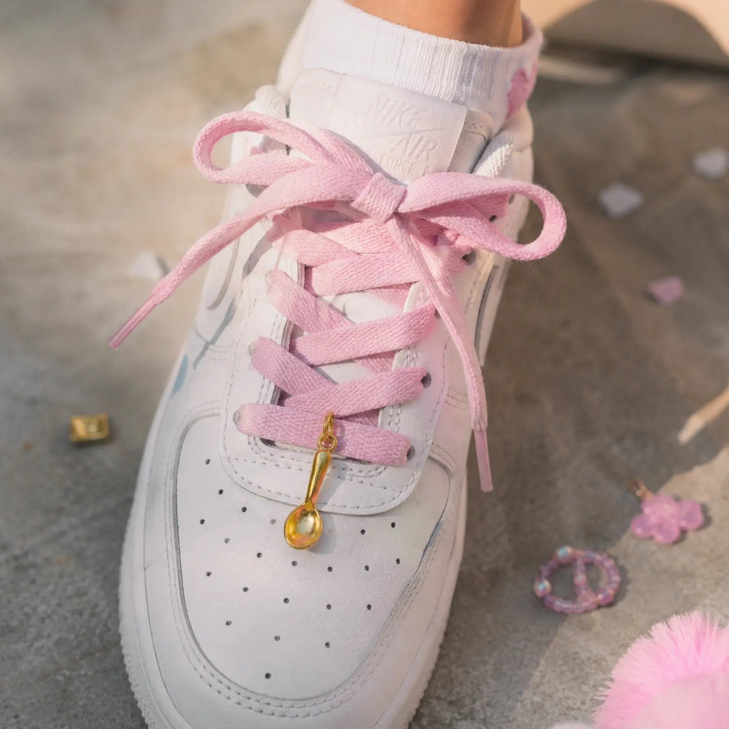 Charm cuillère dorée Lumi accroché à des lacets de sneakers ado adulte