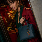 Romy la Magnétique portée sur un sac à main bleu avec charms dorés et colorés en look adulte
